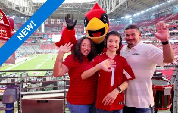 A mom, dad and son with autism pose with Big Red the AZ Cardinals mascot in front of the football field at new Pal Place